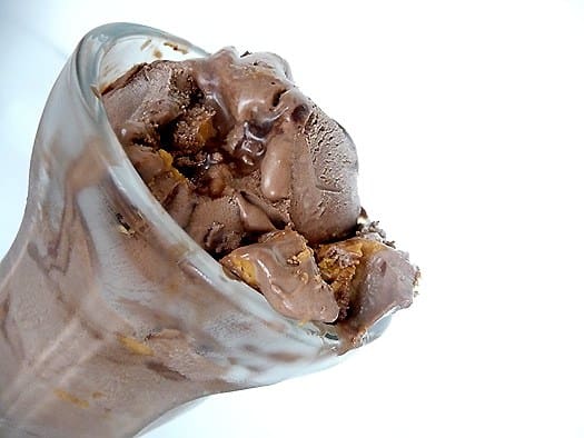Scoops of chocolate fudge swirl peanut butter ice cream in a glass.