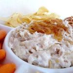 French onion dip topped with sautéed onions in a white bowl.