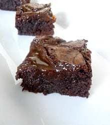 Squares of salted caramel brownies on a white plate.