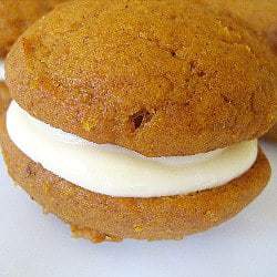 Pumpkin whoopie pie with maple cream cheese filling on a white plate.