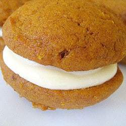Pumpkin whoopie pie with maple cream cheese filling on a white plate.