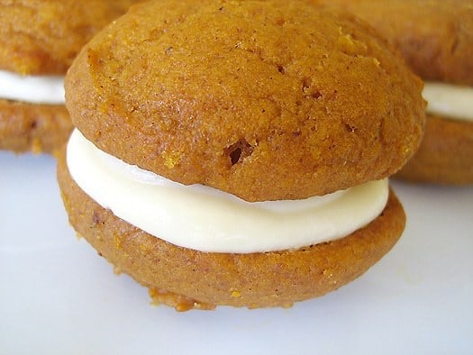 Pumpkin whoopie pies with maple cream cheese filling on a white plate.
