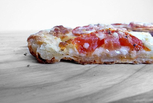 Side view of a white Sicilian pizza on a wood surface.