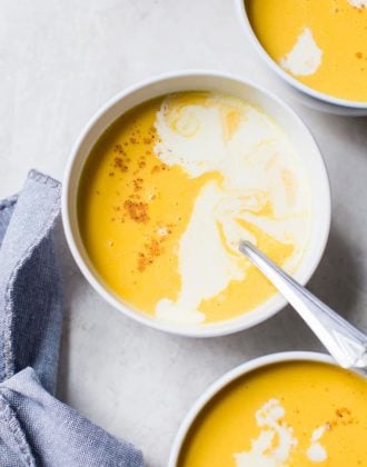 Three bowls of butternut squash soup with a drizzle of cream and pinch of nutmeg.