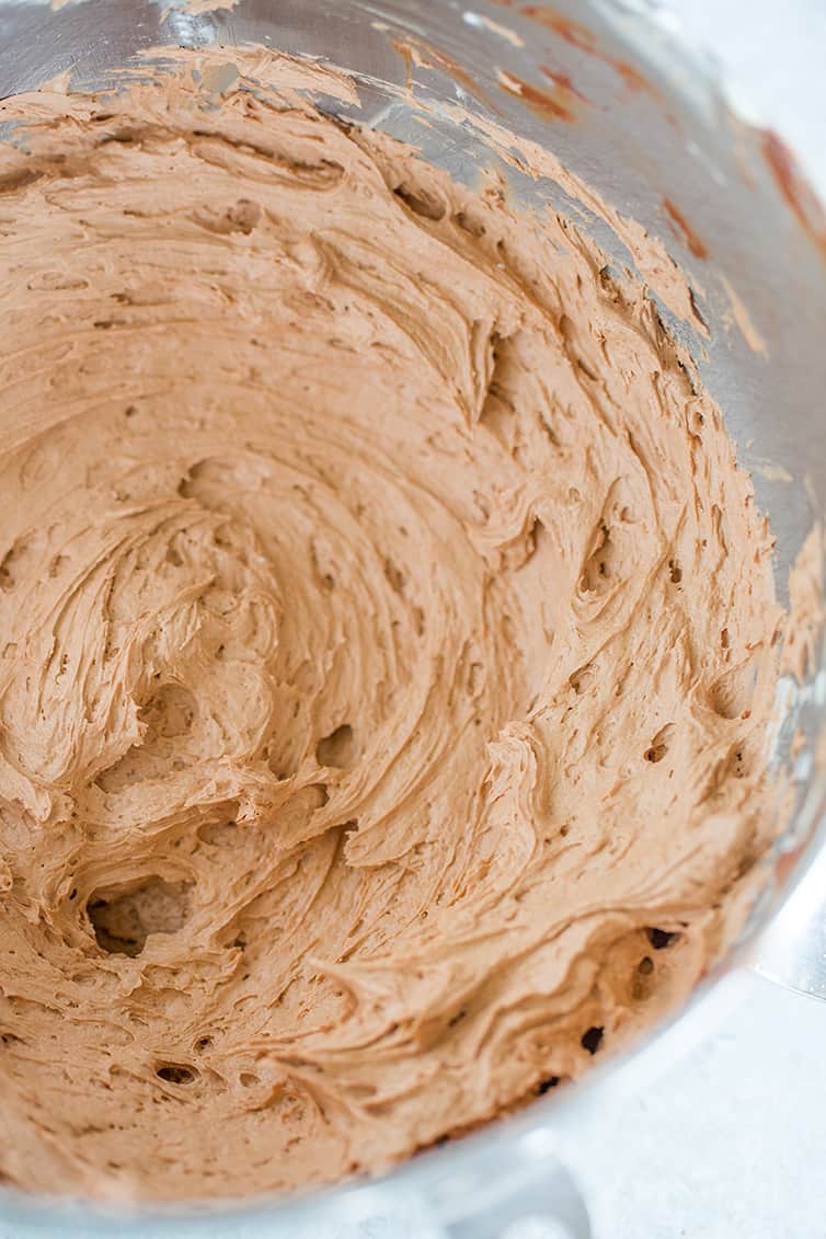 A mixing bowl with chocolate frosting in it.