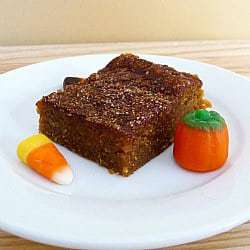 Square of pumpkin pie bars on a white plate with candy corn garnish.