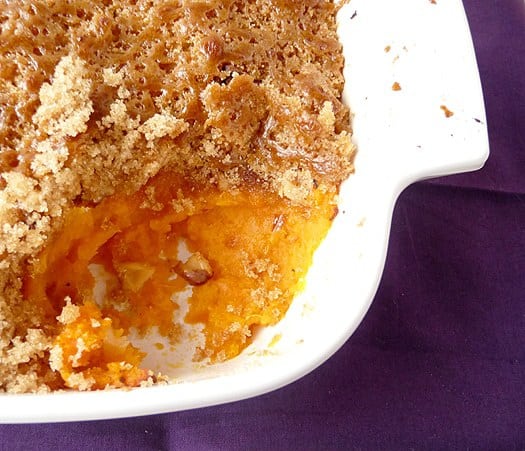 Overhead image of mashed sweet potato brûlée in a casserole dish with a serving scooped out showing the inside texture.