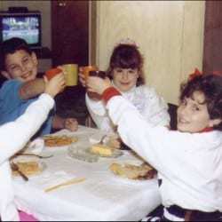 Vintage photo of kids cheers-ing with glasses at a Thanksgiving table.