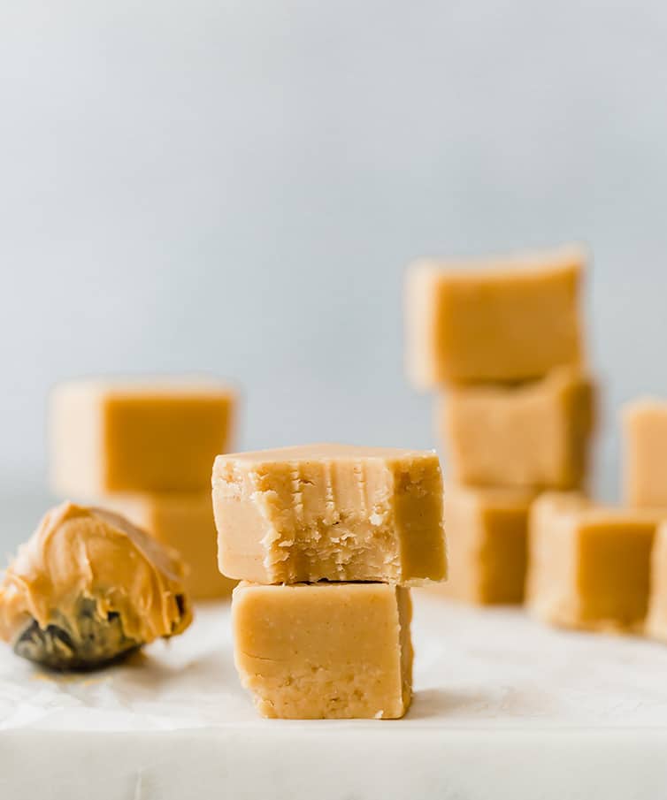 Squares of peanut butter fudge in stacks on a marble slab.