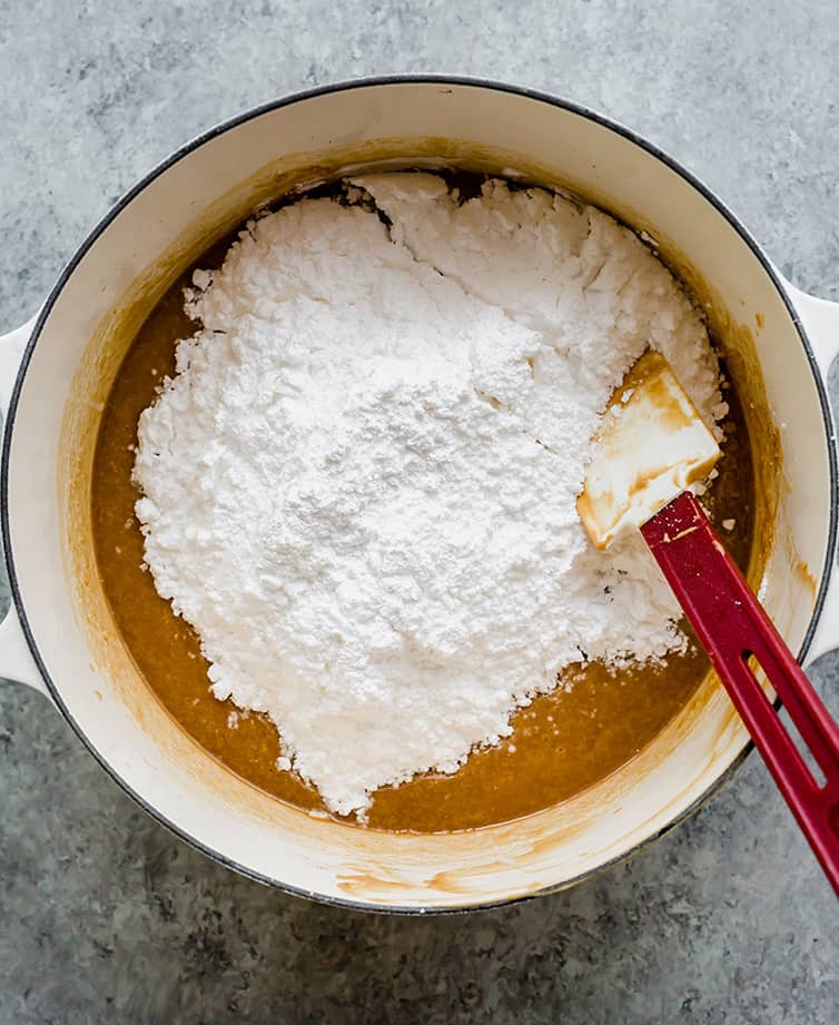 Pot of melted butter and peanut butter with powdered sugar being mixed in.