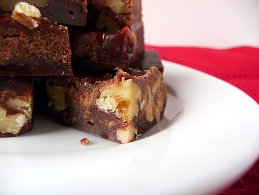 Close up image of chocolate walnut fudge on a white plate.