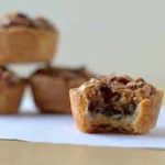 Pecan tassies with a bite taken from one.
