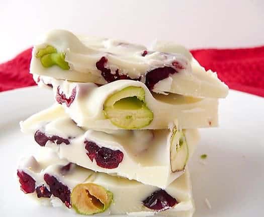 Stack of 4 pieces of pistachio and cranberry white chocolate bark on a white plate.