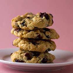 Stack of 4 cranberry white chocolate chip cookies on a white plate.