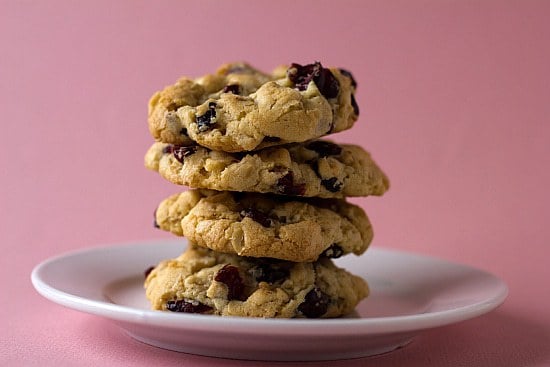 Stack of 4 cranberry white chocolate chip cookies on a white plate.