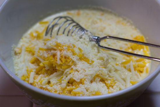 Cheese sauce ingredients in a bowl with a whisk.