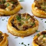 Caramelized onion, mushroom, and gruyere tartlets on a white serving plate.