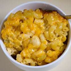 Baked macaroni and cheese in a white bowl with a spoon.