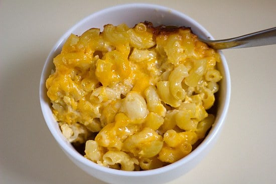 Baked macaroni and cheese in a white bowl with a spoon.