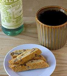 4 pieces of anisette biscotti on a white plate with a cup of coffee.