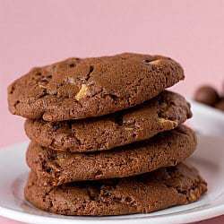 Stack of 4 chocolate malted whopper cookies on a white plate.