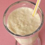 Malted vanilla milkshake in a glass with a straw.