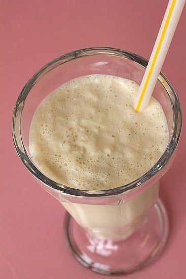 Malted vanilla milkshake in a glass with a straw.