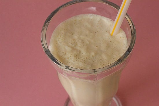 Malted vanilla milkshake in a glass with a straw.