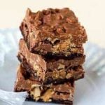Stack of 3 peanut butter cup crunch brownie bars on a white plate.
