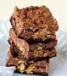Stack of 3 peanut butter cup crunch brownie bars on a white plate.