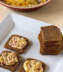 Hot reuben dip spread onto crackers on a white serving tray.