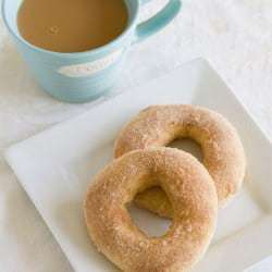 2 cinnamon sugar doughnuts on a white square plate with a cup of coffee.