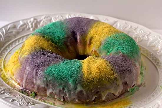 Decorated Mardi Gras king cake on a white serving platter.