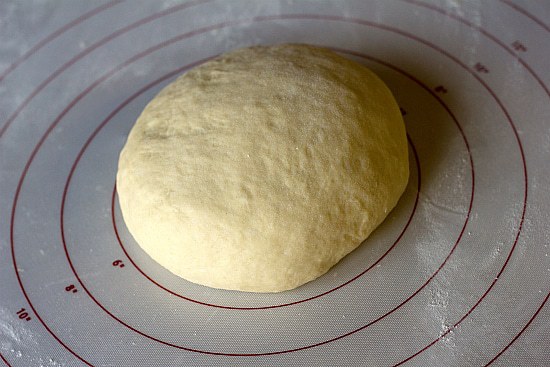 Ball of king cake dough on a silpat baking mat.