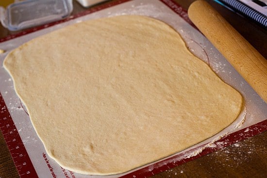 King cake dough rolled into a rectangle on a silpat baking mat.