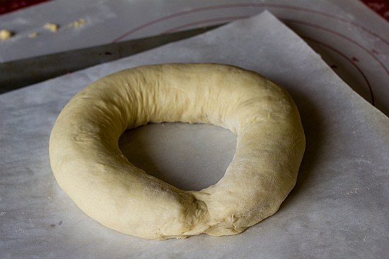 King cake dough shaped into a circle on a parchment paper lined baking sheet before baking.