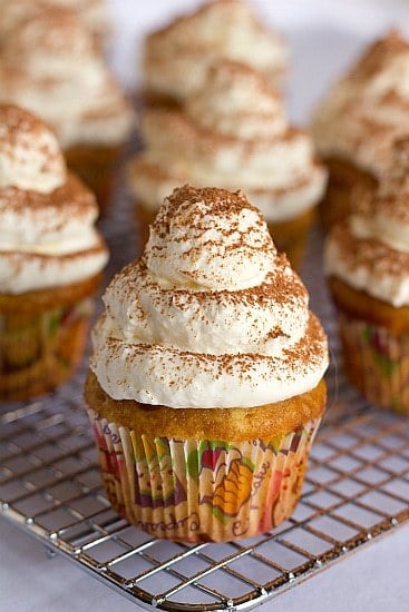 Frosted tiramisu cupcakes on a cooling rack.