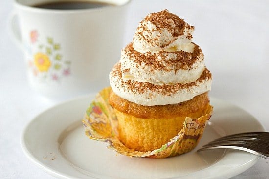 A tiramisu cupcake on a white plate with a fork.