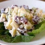 A serving of Waldorf salad on lettuce on a white plate.