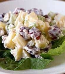 A serving of Waldorf salad on lettuce on a white plate.
