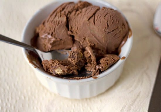 Scoops of chocolate peanut butter cup ice cream in a white bowl with a spoon.