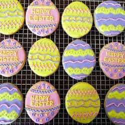 Overhead image of sugar cookies decorated like Easter eggs on a cooling rack.