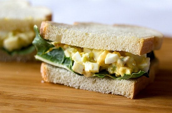 Egg salad sandwich on a wood serving board.