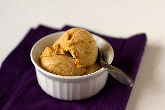 Scoops of salted caramel ice cream in a white bowl with a spoon.