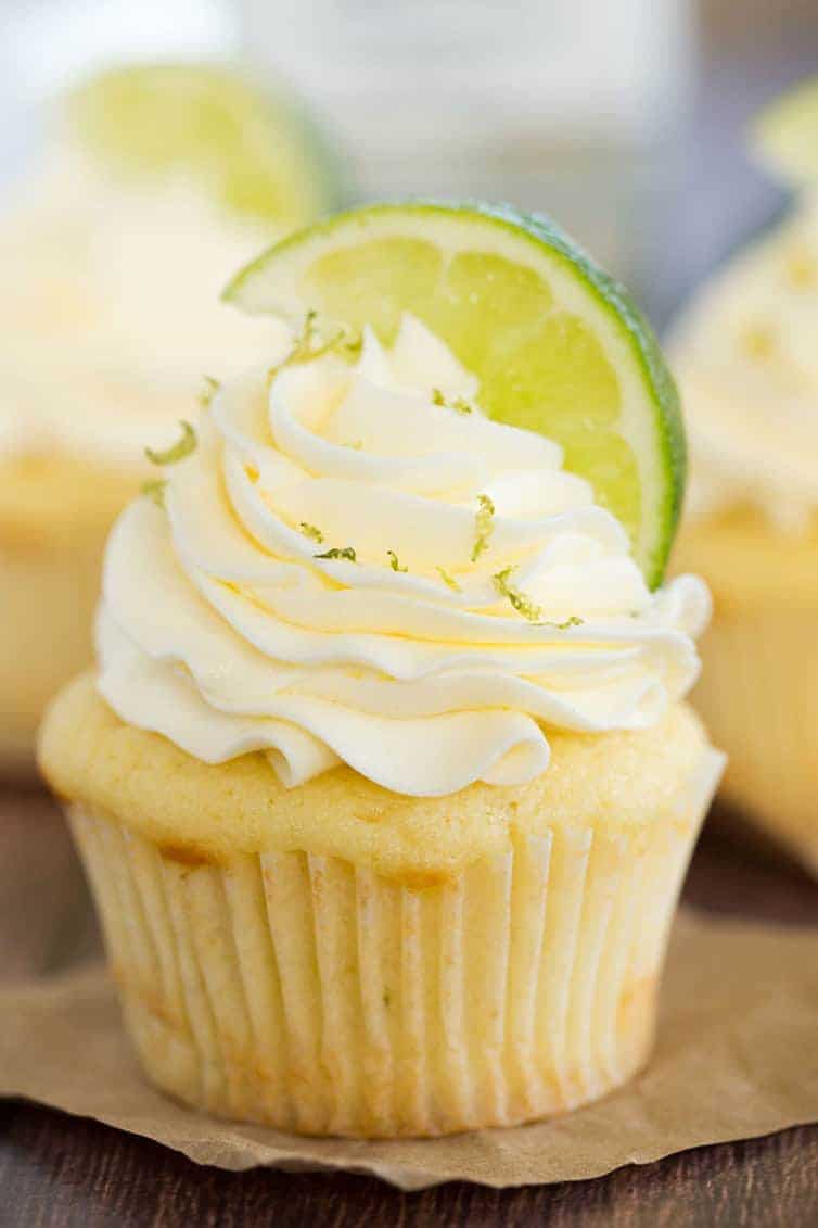 Vanilla cupcake topped with vanilla frosting, sprinkled with lime zest and topped with lime wedge.