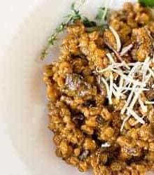 A serving of mushroom barley risotto on a white plate.