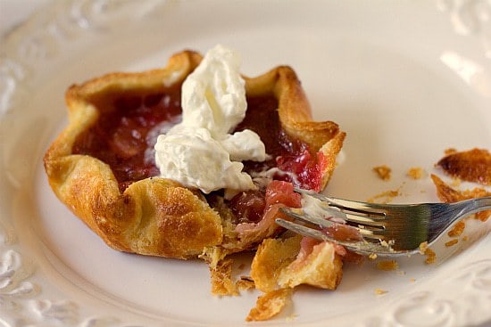 Rhubarb pie tartlet on a white plate with a fork.