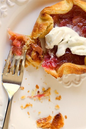 Overhead image of a rhubarb pie tartlet on a white plate with a fork.