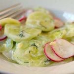 Creamy cucumber salad in a white bowl with a fork.