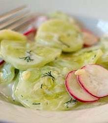 Creamy cucumber salad in a white bowl with a fork.